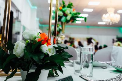 Salle de réception élégante avec des tables dressées, des verres à pied et un lustre lumineux au plafond.