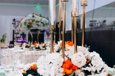Salle de réception élégante avec des tables dressées, des verres à pied et un lustre lumineux au plafond.