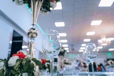 Salle de réception élégante avec des tables dressées, des verres à pied et un lustre lumineux au plafond.