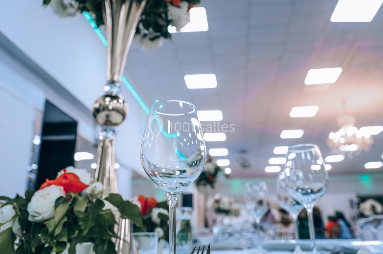 Verres à pied et compositions florales sur une table élégamment dressée dans une salle lumineuse.