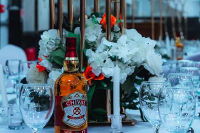 Salle de réception élégante avec des tables dressées, des verres à pied et un lustre lumineux au plafond.
