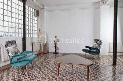 Façade d'un bâtiment avec une grande fenêtre en pavés de verre, une porte ouverte et un banc blanc devant.
