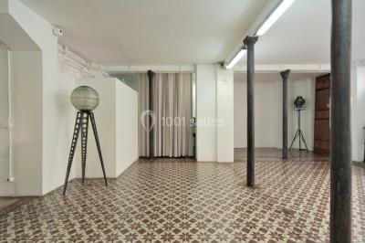 Façade d'un bâtiment avec une grande fenêtre en pavés de verre, une porte ouverte et un banc blanc devant.