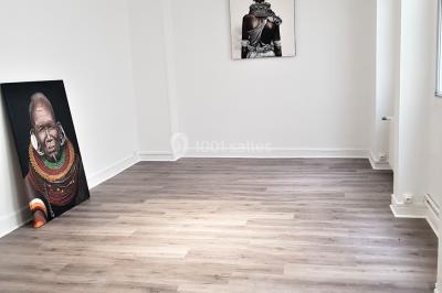 Façade d'un bâtiment avec une grande fenêtre en pavés de verre, une porte ouverte et un banc blanc devant.