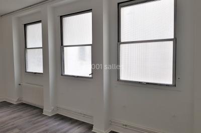 Façade d'un bâtiment avec une grande fenêtre en pavés de verre, une porte ouverte et un banc blanc devant.