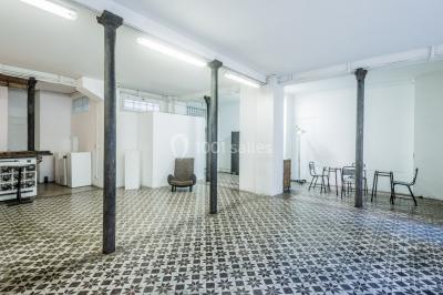 Façade d'un bâtiment avec une grande fenêtre en pavés de verre, une porte ouverte et un banc blanc devant.