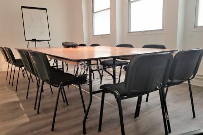 Façade d'un bâtiment avec une grande fenêtre en pavés de verre, une porte ouverte et un banc blanc devant.