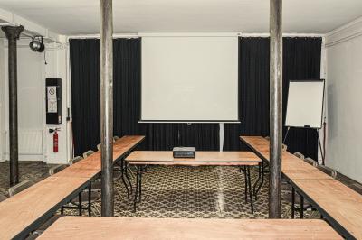 Façade d'un bâtiment avec une grande fenêtre en pavés de verre, une porte ouverte et un banc blanc devant.