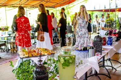 Miroir orné de motifs dorés reflétant une salle de restaurant avec cheminée, tables dressées et chaises rouges.