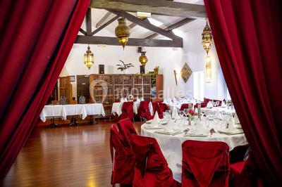 Miroir orné de motifs dorés reflétant une salle de restaurant avec cheminée, tables dressées et chaises rouges.