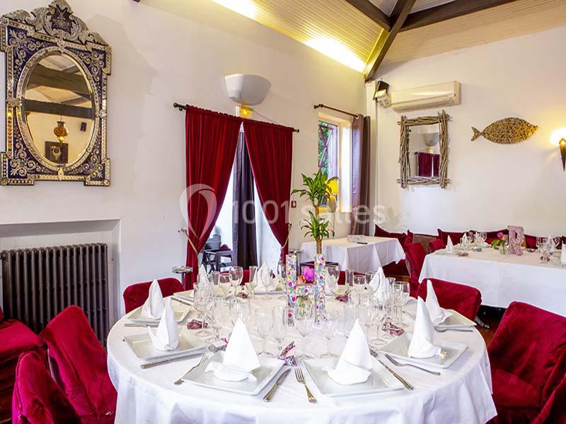 Salle de réception élégante avec tables rondes dressées, nappes blanches, serviettes pliées et décorations raffinées.