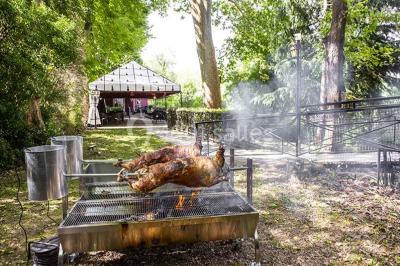 Miroir orné de motifs dorés reflétant une salle de restaurant avec cheminée, tables dressées et chaises rouges.