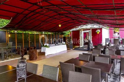 Miroir orné de motifs dorés reflétant une salle de restaurant avec cheminée, tables dressées et chaises rouges.