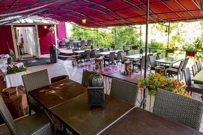 Miroir orné de motifs dorés reflétant une salle de restaurant avec cheminée, tables dressées et chaises rouges.