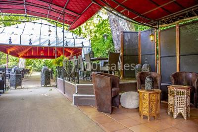 Miroir orné de motifs dorés reflétant une salle de restaurant avec cheminée, tables dressées et chaises rouges.
