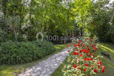 Miroir orné de motifs dorés reflétant une salle de restaurant avec cheminée, tables dressées et chaises rouges.