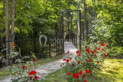 Miroir orné de motifs dorés reflétant une salle de restaurant avec cheminée, tables dressées et chaises rouges.