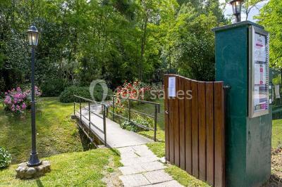 Miroir orné de motifs dorés reflétant une salle de restaurant avec cheminée, tables dressées et chaises rouges.