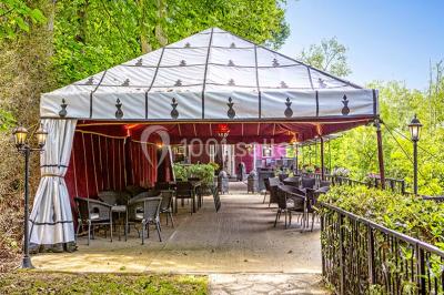 Miroir orné de motifs dorés reflétant une salle de restaurant avec cheminée, tables dressées et chaises rouges.