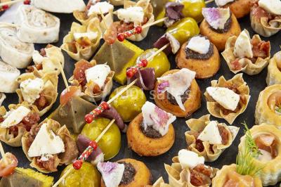 Miroir orné de motifs dorés reflétant une salle de restaurant avec cheminée, tables dressées et chaises rouges.