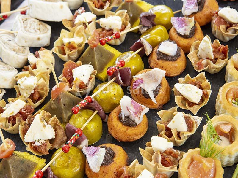Plateau de bouchées apéritives variées comprenant feuilletés, brochettes, olives et petits gâteaux salés.