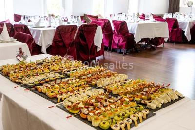 Miroir orné de motifs dorés reflétant une salle de restaurant avec cheminée, tables dressées et chaises rouges.