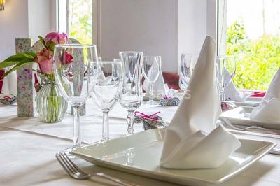 Miroir orné de motifs dorés reflétant une salle de restaurant avec cheminée, tables dressées et chaises rouges.