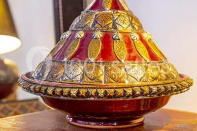 Miroir orné de motifs dorés reflétant une salle de restaurant avec cheminée, tables dressées et chaises rouges.