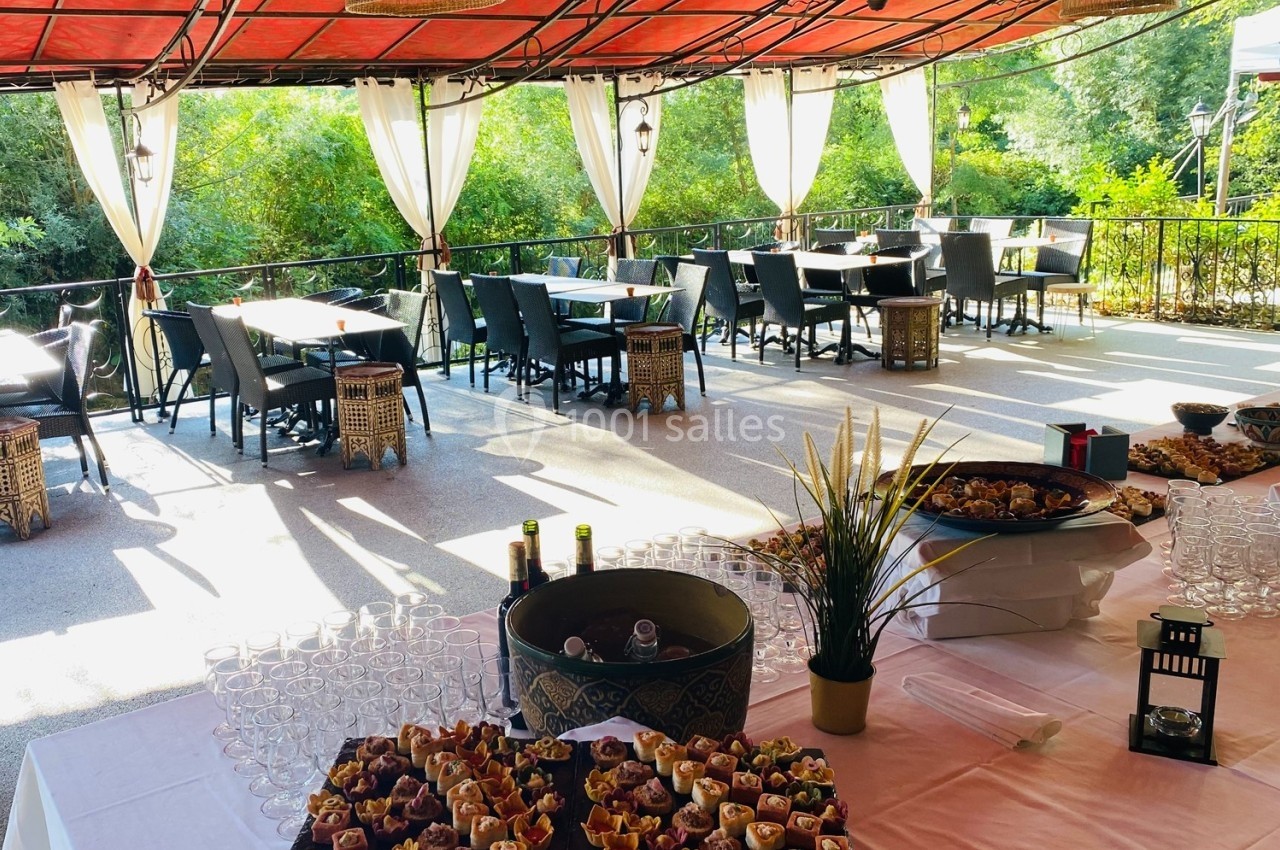 Buffet de petits fours disposé sur une table sous une terrasse couverte, avec vue sur un jardin verdoyant.