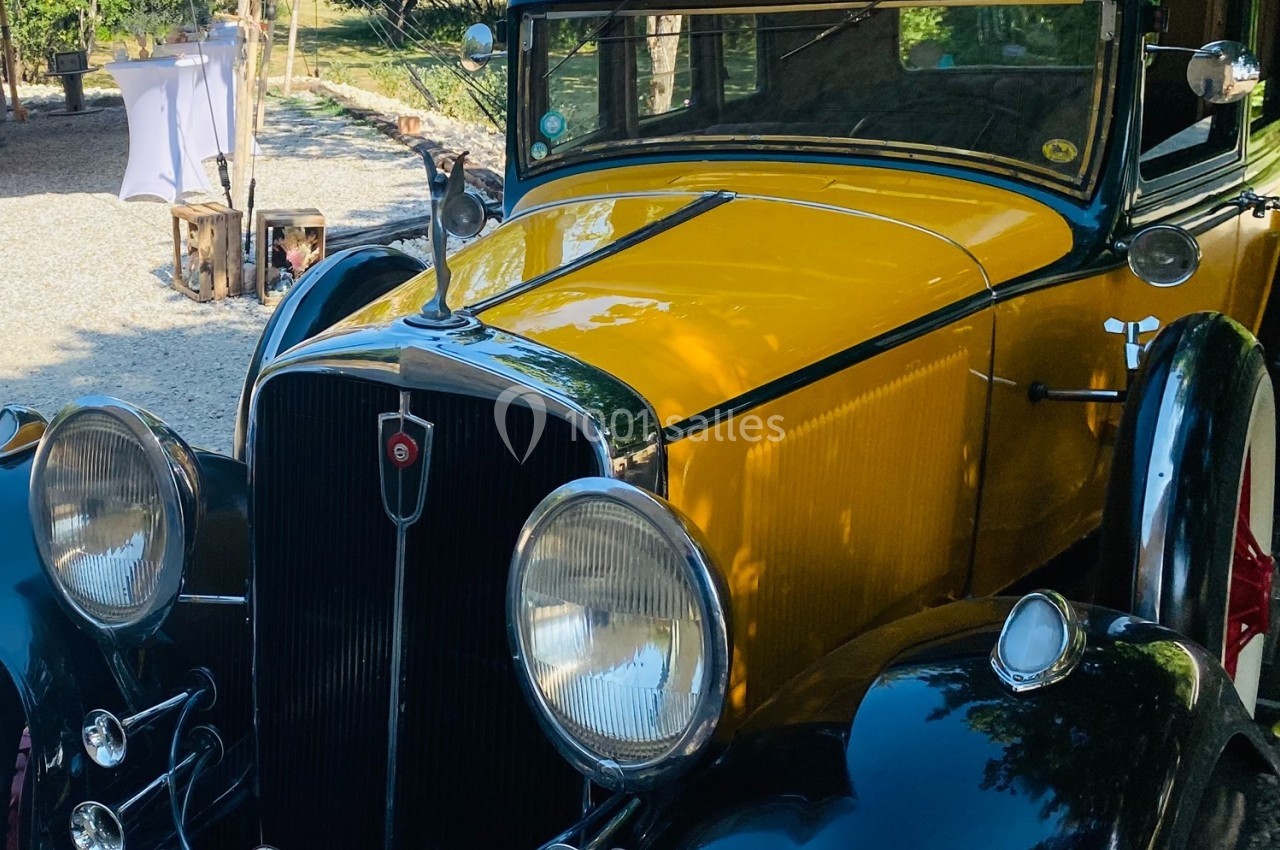 Voiture ancienne jaune et noire stationnée en extérieur, avec des détails chromés et des phares ronds.