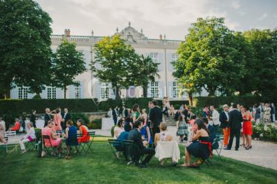 Miniature Location salle Piolenc (Vaucluse) - Château Beauchêne #2 Un couple en tenue de mariage sourit sur les marches d'un escalier en pierre devant une maison entourée de végétation.
