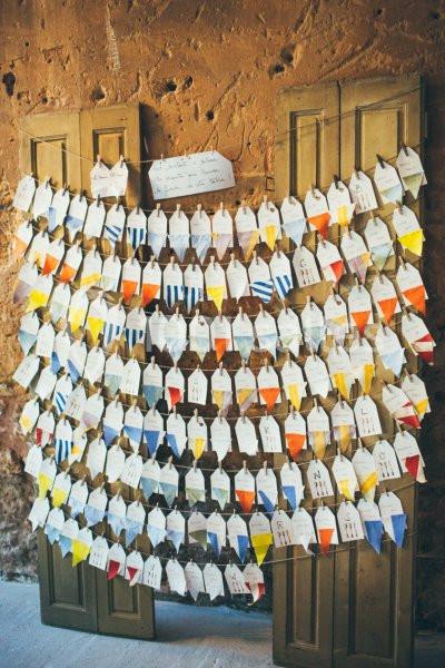 Location salle Piolenc (Vaucluse) - Château Beauchêne #9 Des enveloppes colorées suspendues sur des cordes devant un mur en pierre et des panneaux en bois.