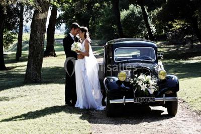 Miniature Location salle Piolenc (Vaucluse) - Château Beauchêne #15 Un couple en tenue de mariage sourit sur les marches d'un escalier en pierre devant une maison entourée de végétation.