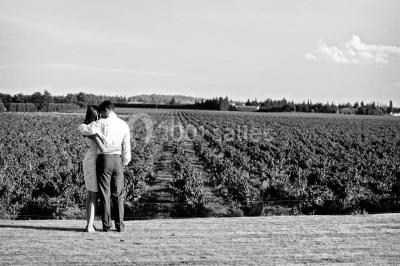 Miniature Location salle Piolenc (Vaucluse) - Château Beauchêne #14 Un couple en tenue de mariage sourit sur les marches d'un escalier en pierre devant une maison entourée de végétation.
