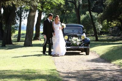 Miniature Location salle Piolenc (Vaucluse) - Château Beauchêne #16 Un couple en tenue de mariage sourit sur les marches d'un escalier en pierre devant une maison entourée de végétation.