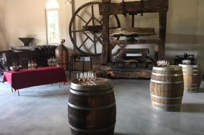 Salle avec de grandes presses anciennes en bois et une longue table dressée pour un repas.