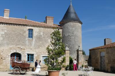 Un couple marche dans le jardin d'un château ancien entouré de verdure par une journée ensoleillée.