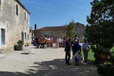 Un couple marche dans le jardin d'un château ancien entouré de verdure par une journée ensoleillée.