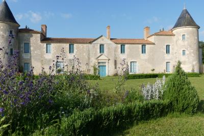 Un couple marche dans le jardin d'un château ancien entouré de verdure par une journée ensoleillée.