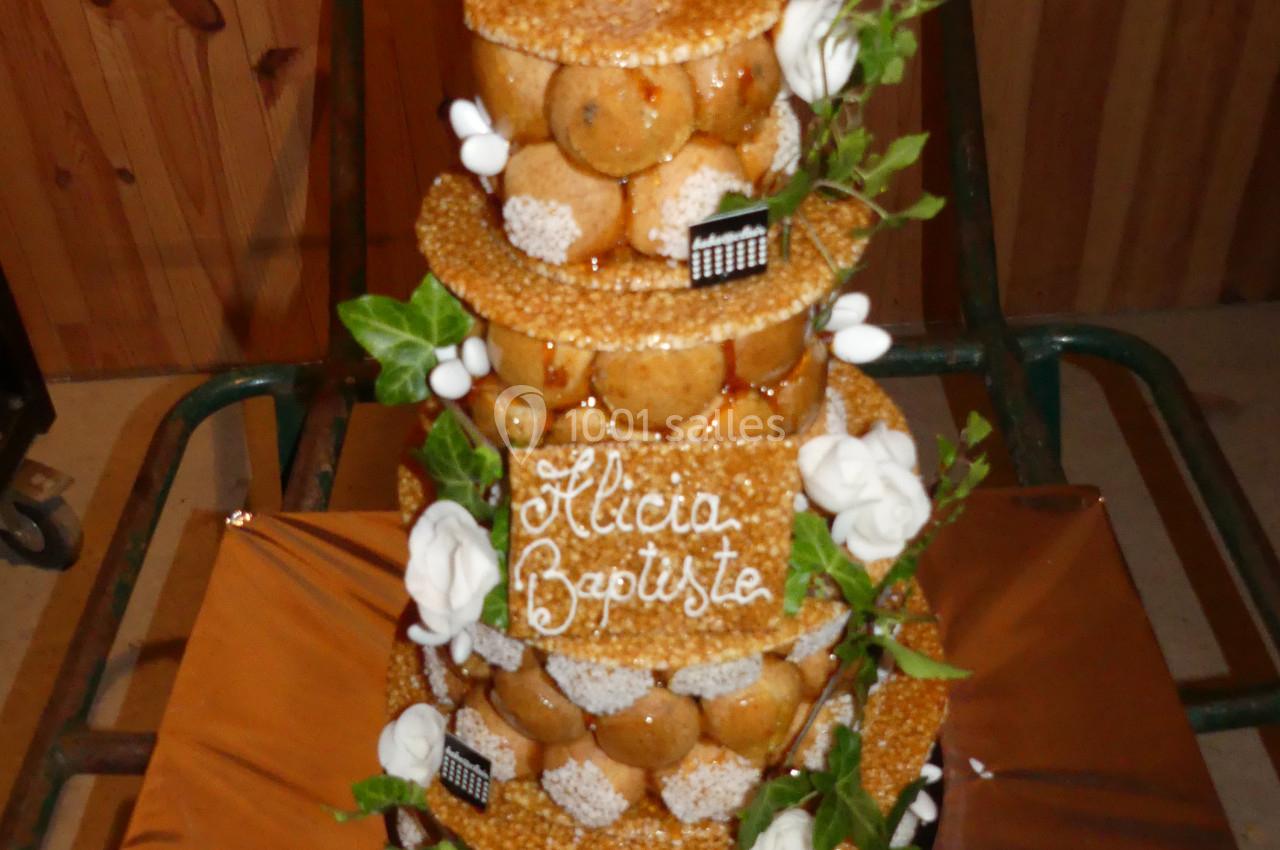 Pièce montée en choux décorée de feuilles, fleurs en sucre et inscription ’Alicia Baptiste’ sur une plaque.