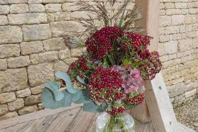 Un couple marche dans le jardin d'un château ancien entouré de verdure par une journée ensoleillée.