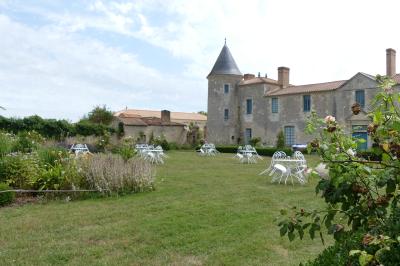Un couple marche dans le jardin d'un château ancien entouré de verdure par une journée ensoleillée.