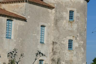 Un couple marche dans le jardin d'un château ancien entouré de verdure par une journée ensoleillée.
