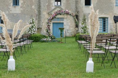 Un couple marche dans le jardin d'un château ancien entouré de verdure par une journée ensoleillée.
