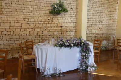 Un couple marche dans le jardin d'un château ancien entouré de verdure par une journée ensoleillée.