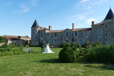 Un couple marche dans le jardin d'un château ancien entouré de verdure par une journée ensoleillée.