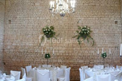 Un couple marche dans le jardin d'un château ancien entouré de verdure par une journée ensoleillée.
