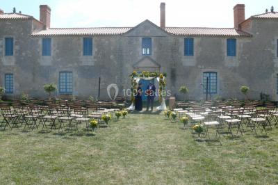 Un couple marche dans le jardin d'un château ancien entouré de verdure par une journée ensoleillée.
