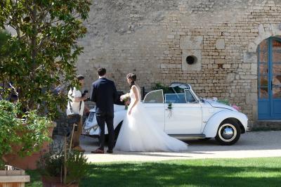 Un couple marche dans le jardin d'un château ancien entouré de verdure par une journée ensoleillée.