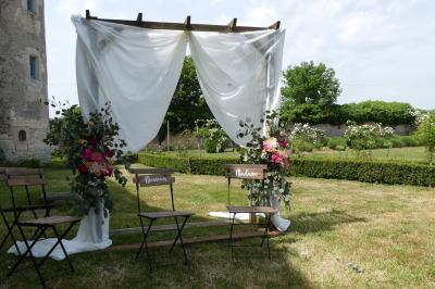 Un couple marche dans le jardin d'un château ancien entouré de verdure par une journée ensoleillée.
